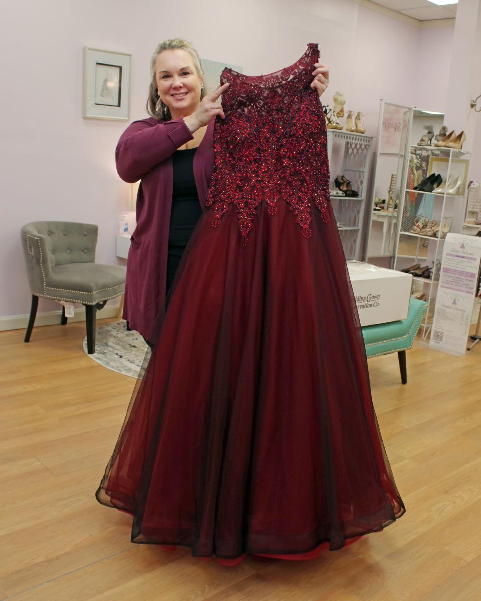 Miss Louise Prom Closet owner Julie Costa shows a dress that she especially likes, a fitted evening dress in red, on Thursday, Jan. 13, 2022 at her shop in Bridgewater.