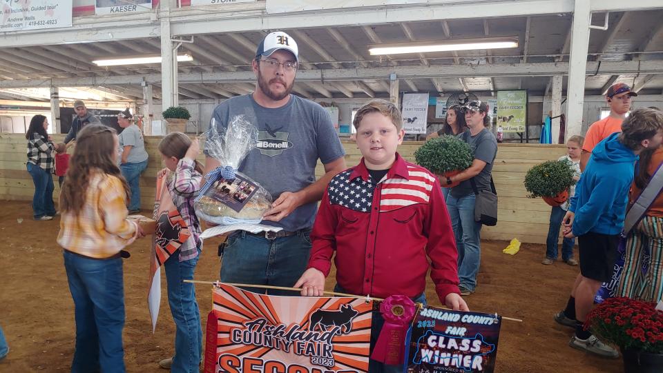 Rhett Bowman and his dad, Jon Bowman, are ready to gift the buyer of Rhett's market hog with an apple pie on Friday morning at the Ashland County Fair.