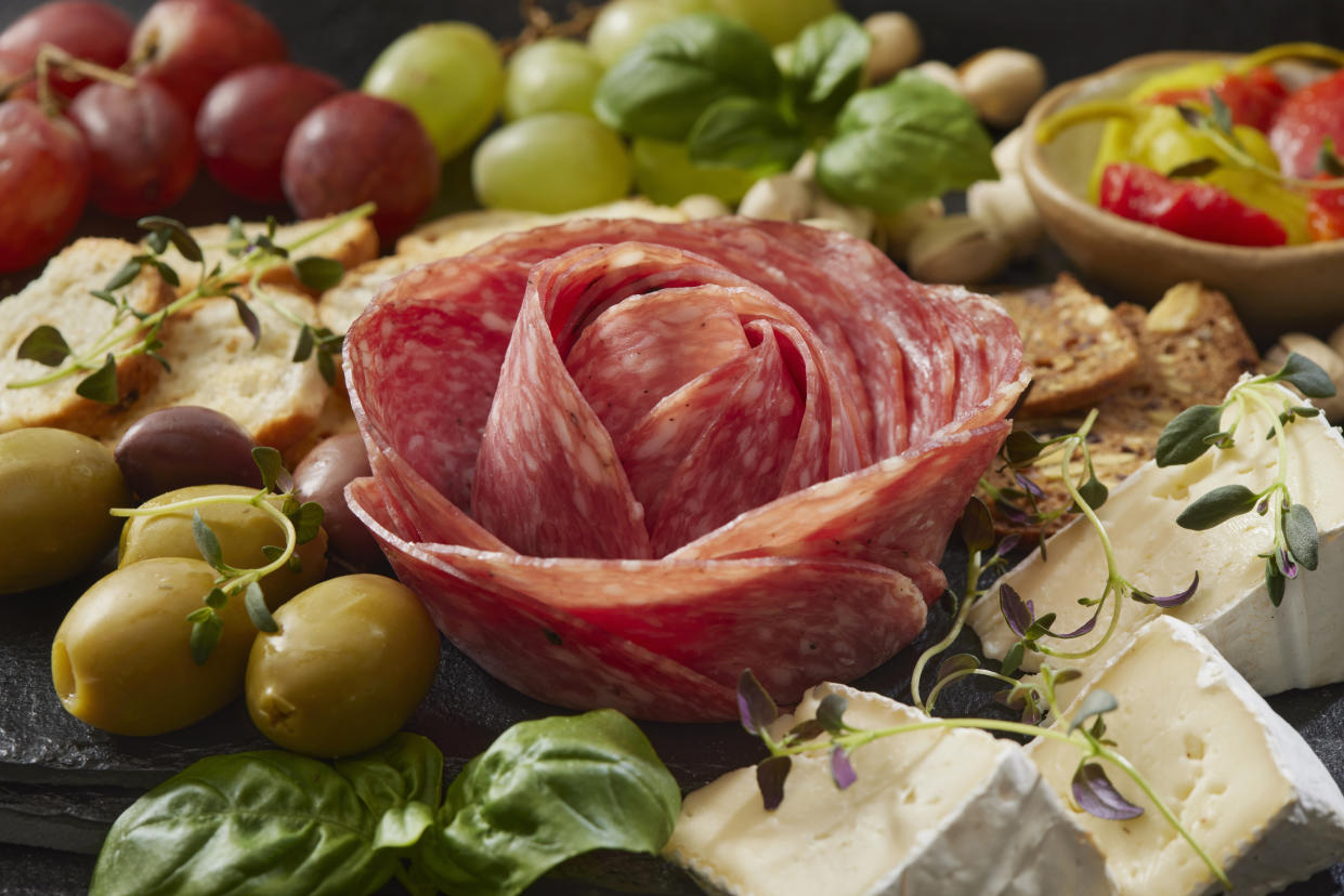 Closeup of charcuterie board with meat, cheese, olives, grapes and sliced bread.