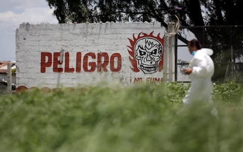 A forensic technician walks by a wall reading "Danger" while inspecting the site - Credit: Daniel Becerril/Reuters