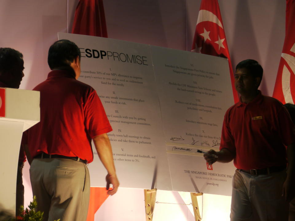 Candidates John Tan (left) and James Gomez (right) sign the ‘SDP Promise’. (Yahoo! photo/ Faris Mokhtar) 