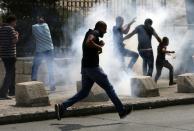 Palestinians take cover as Israeli security forces throw stun grenades during clashes in Jerusalem's Old City outside the Al-Aqsa mosque compound on October 2, 2015