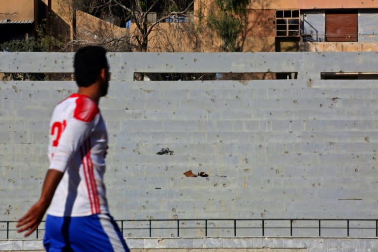 A Syrian player walks past shrapnel riddled stands during a football match on April 16, 2018 at a stadium in Raqa that Islamic State used as a prison