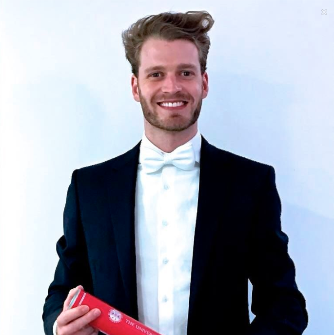 Louis, Viscount Althorp poses in a tuxedo with his degree.  