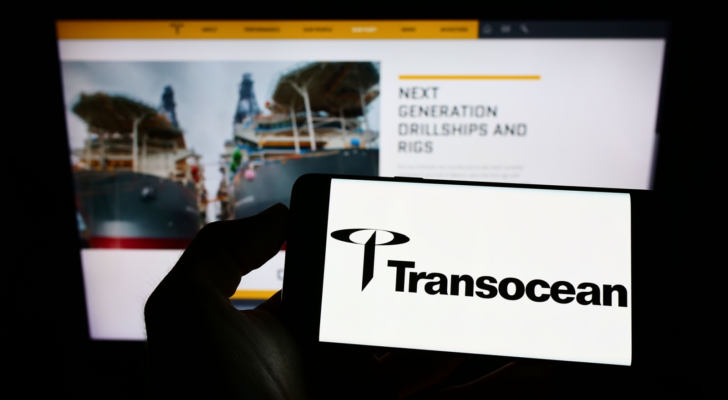 Person holding smartphone with logo of offshore drilling company Transocean Ltd. (RIG) on screen in front of website. Focus on phone display. Unmodified photo.