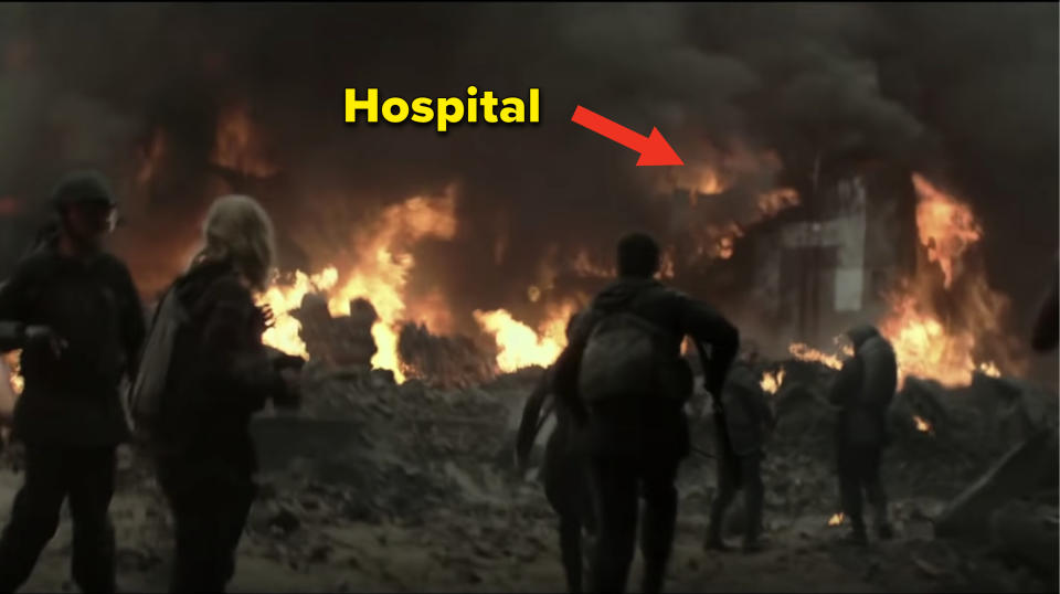 A crumbled building covered in smoke and flames with the caption hospital and an arrow