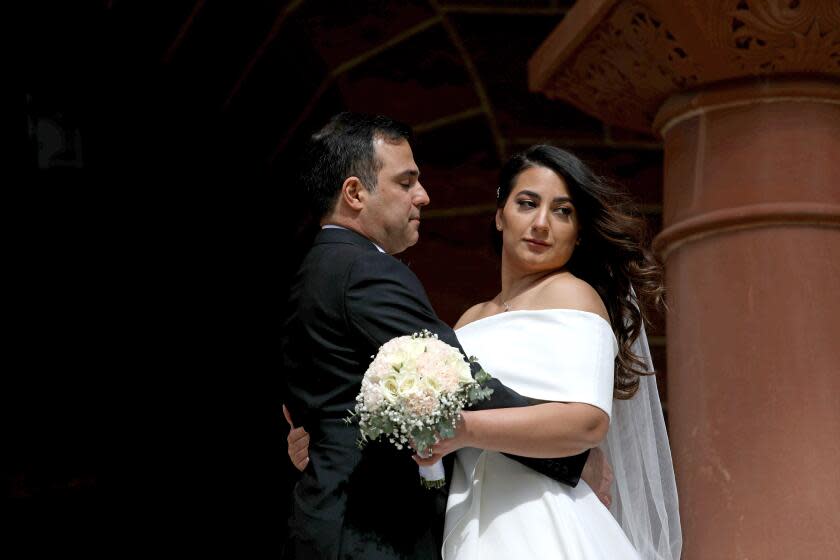 SANTA ANA, CA - FEBRUARY 22: A photographer helps a couple pose for photos before tying the knot on unforgettable 2/22/22 wedding date at the Old County Courthouse in downtown on Tuesday, Feb. 22, 2022 in Santa Ana, CA. For those looking for marriage bliss on a once-in-a-lifetime and easy to remember marriage anniversary date, your day is just around the corner. This upcoming Twos Day, which is Tuesday, February 22, 2022 (2-22-22), Orange County Clerk-Recorder Hugh Nguyen will be offering extended hours at his offices in Anaheim, Laguna Hills and at the Old Orange County Courthouse in Santa Ana. (Gary Coronado / Los Angeles Times)