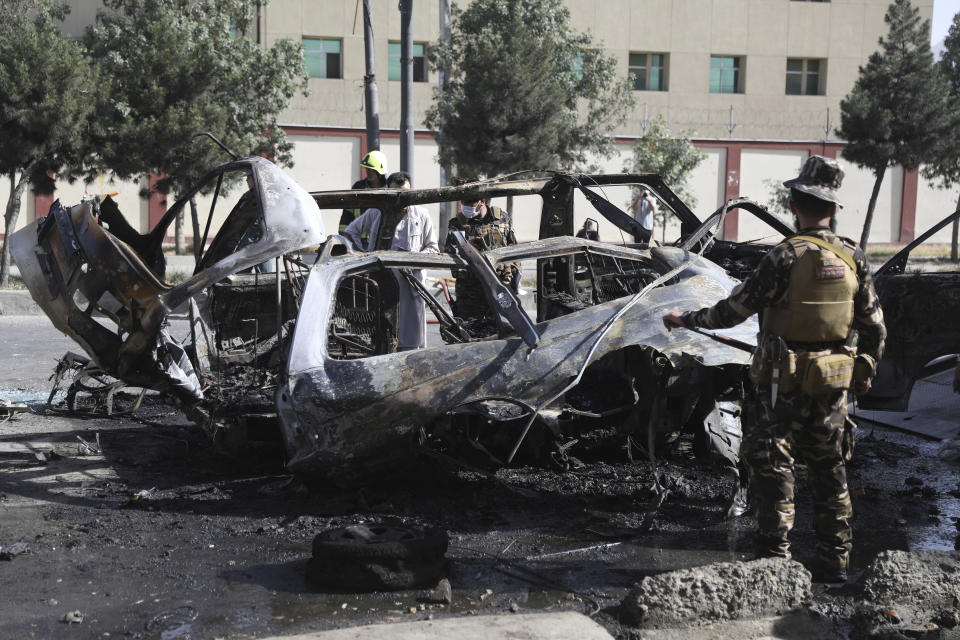 Afghan security personnel inspect the site of a bomb explosion in Kabul, Afghanistan, Saturday, June 12, 2021. Separate bombs hit two minivans in a mostly Shiite neighborhood in the Afghan capital Saturday, killing several people and wounding others, the Interior Ministry said. (AP Photo/Rahmat Gul)