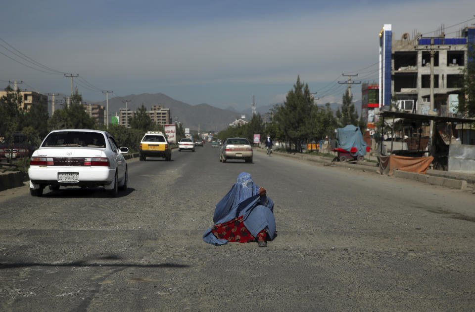 A woman waits to receive alms during the holy fasting month of Ramadan in Kabul, Afghanistan, Sunday, May 3, 2020. Muslims across the world are observing Ramadan when the faithful refrain from eating, drinking and smoking from dawn to dusk. (AP Photo/Rahmat Gul)