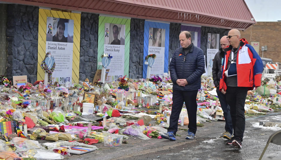 Colorado Gov. Jared Polis, left, walks in front of a memorial set up outside Club Q in Colorado Springs, Colo., Tuesday, Nov. 29, 2022. Polis, the first openly gay man to be elected governor in the United States, paid tribute to the victims who were killed in last week's mass shooting at the gay nightclub. (Jerilee Bennett/The Gazette via AP)