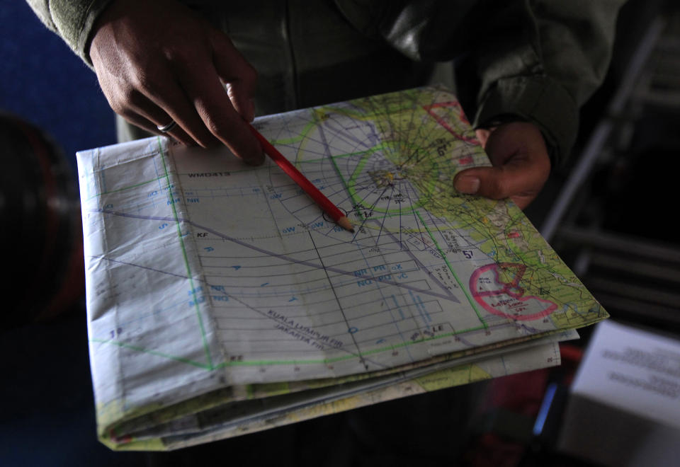 A pilot of a Royal Malaysian Air Force CN-235 aircraft shows a map during a search and rescue operation for the missing Malaysia Airlines plane over the waters at Malacca straits, Malaysia, Thursday, March 13, 2014. Planes sent Thursday to check the spot where Chinese satellite images showed possible debris from the missing Malaysian jetliner found nothing, Malaysia's civil aviation chief said, deflating the latest lead in the six-day hunt. The hunt for the missing Malaysia Airlines flight 370 has been punctuated by false leads since it disappeared with 239 people aboard about an hour after leaving Kuala Lumpur for Beijing early Saturday. (AP Photo/Lai Seng Sin)