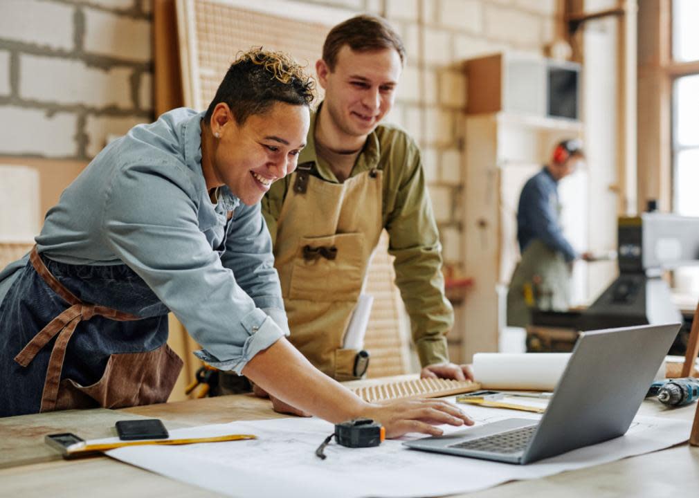 Two carpenters reviewing work on laptop.