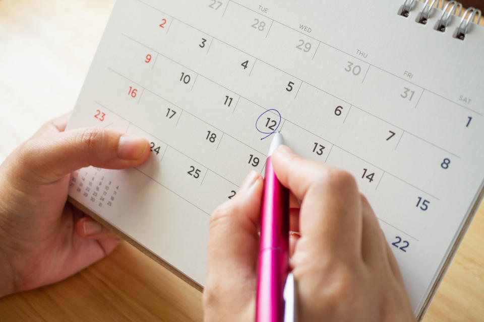 A person circling a date on a calendar with a pen.