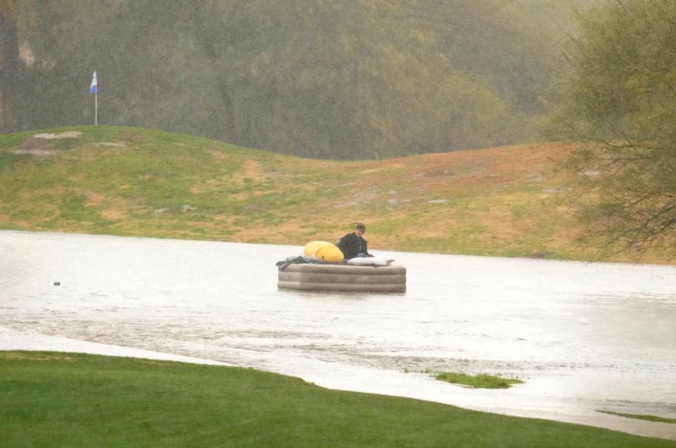 A man floats on a mattress in the floodwaters that run through Stonecreek Golf Club in Phoenix as a Pacific winter storm passes through Arizona on Jan. 23, 2024.