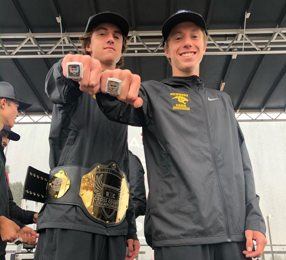 Colin Sahlman (left), wearing the championship belt he won for finishing first overall, and Aaron Sahlman show off the rings they received for achieving All-American status after the Newbury Park boys cross country team won a national title in Alabama on Saturday.