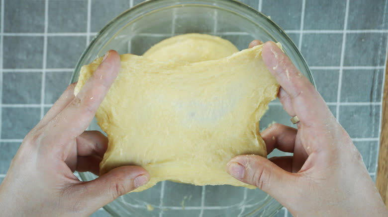 Person stretching dough into windowpane