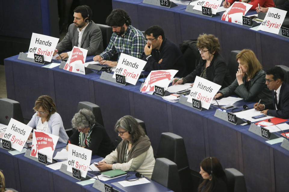 MEPs with placards protesting against the strikes launched by the UK, France and the UK (Getty)