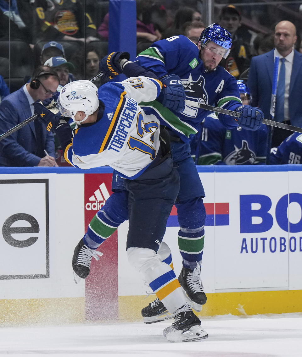 Vancouver Canucks' J.T. Miller, right, checks St. Louis Blues' Alexei Toropchenko during the first period of an NHL hockey game Wednesday, Jan. 24, 2024, in Vancouver, British Columbia. (Darryl Dyck/The Canadian Press via AP)