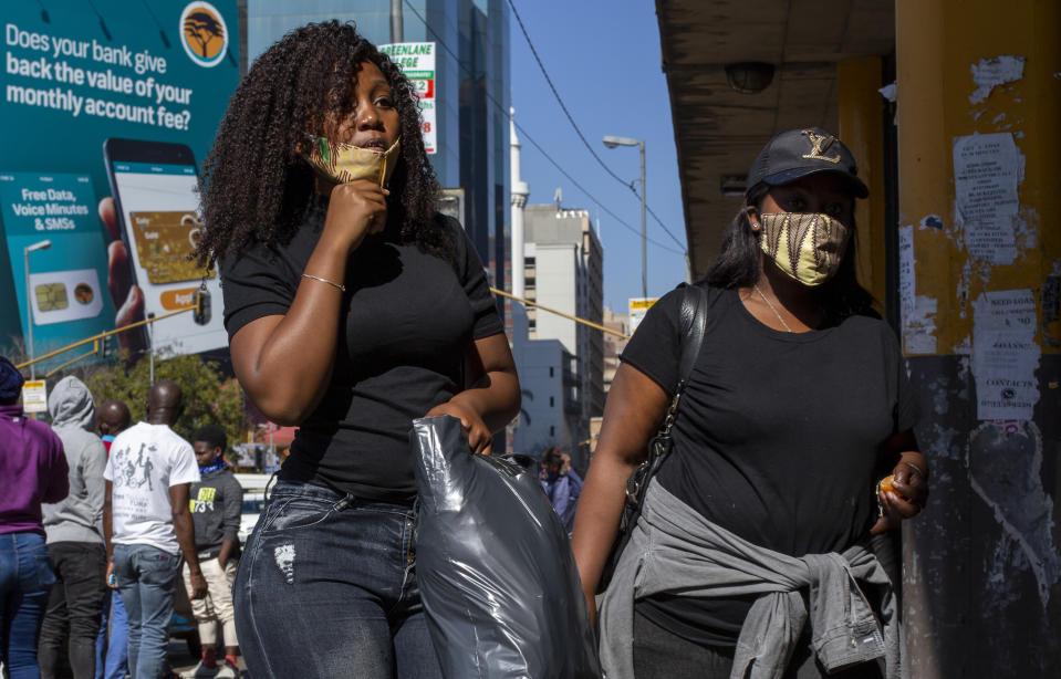 People wearing face masks to protect against coronavirus, walk on the street in downtown Johannesburg, South Africa, Monday, May 11, 2020. (AP Photo/Themba Hadebe)