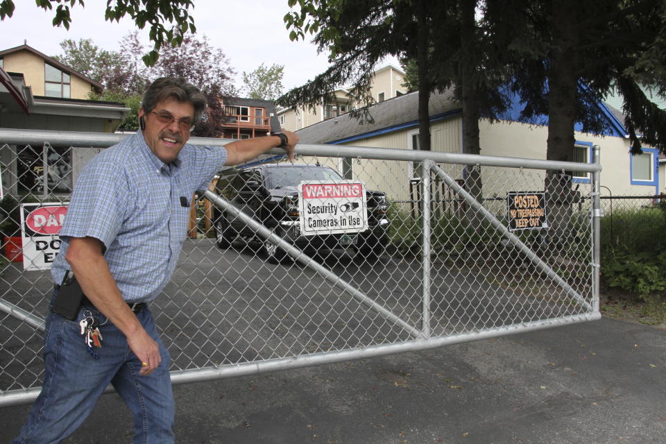 Danny Parish poses for a photo on Wednesday, July 26, 2023, as he closes the sliding gate he installed at his driveway across the street from Sullivan Arena in Anchorage, Alaska. Parish said some bad acts by homeless people made his life "a holy hell" the last three winters the arena has been a homeless shelter. Even though Anchorage Mayor Dave Bronson said the arena would not be used as a mass shelter this winter, Parish said he is selling his home of 29 years and moving out of state because he anticipates the city will have no option but to open it again. (AP Photo/Mark Thiessen)