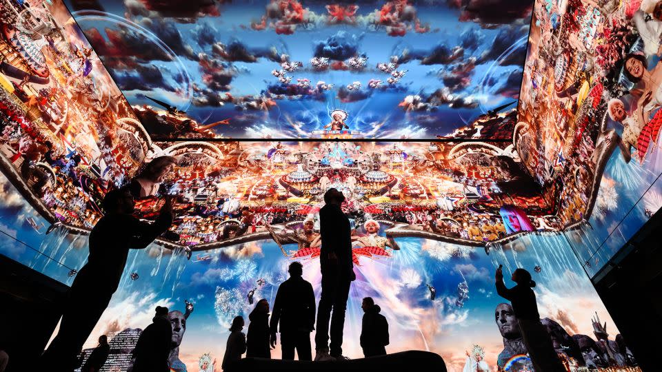 People pose for photographs at Marco Brambilla’s new work "Heaven’s Gate" on the 16K screens of the Outernet London display on January 20, 2023 in London. - Leon Neal/Getty Images