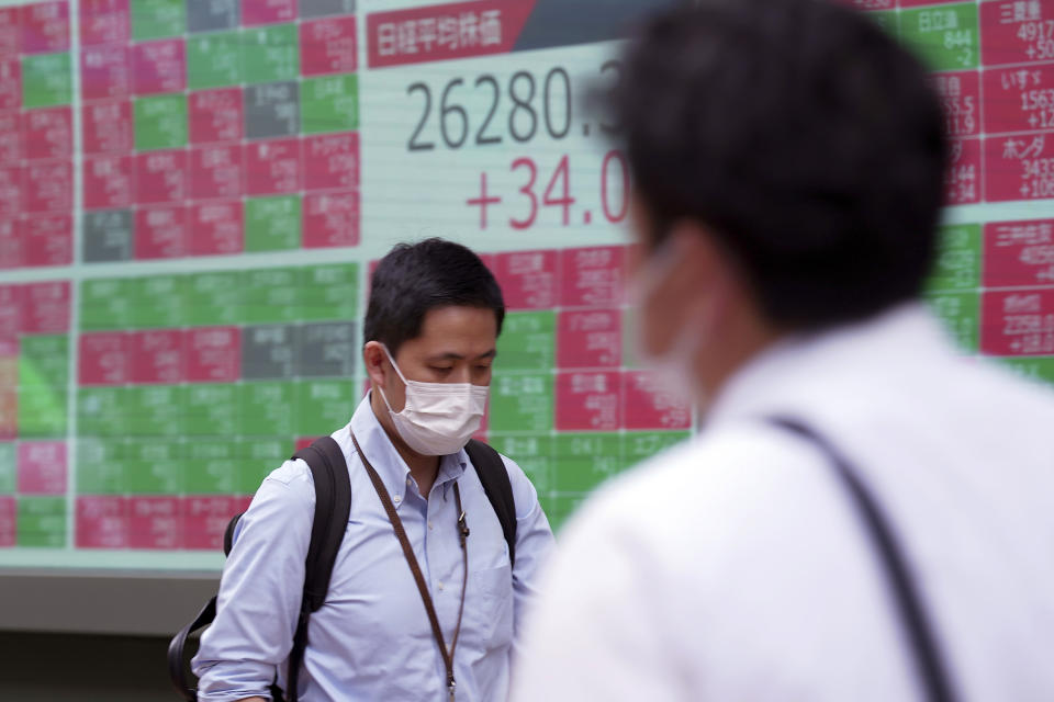 A man wearing a protective mask walks in front of an electronic stock board showing Japan's Nikkei 225 index at a securities firm Wednesday, June 22, 2022, in Tokyo. Asian shares were mostly lower Wednesday as markets shrugged off a Wall Street rally and awaited congressional testimony by Federal Reserve Chair Jerome Powell. (AP Photo/Eugene Hoshiko)