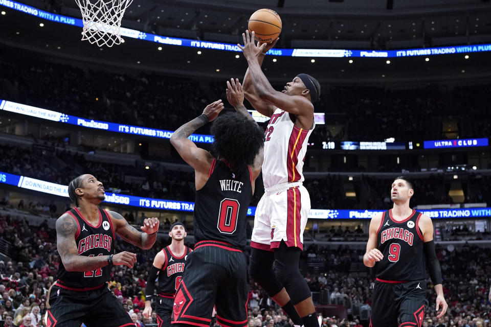 Miami Heat forward Jimmy Butler, second from right, goes up to shoot against Chicago Bulls guard Coby White (0) as Bulls forward DeMar DeRozan, left, watches during the first half of an NBA basketball game in Chicago, Saturday, Nov. 18, 2023. (AP Photo/Nam Y. Huh)