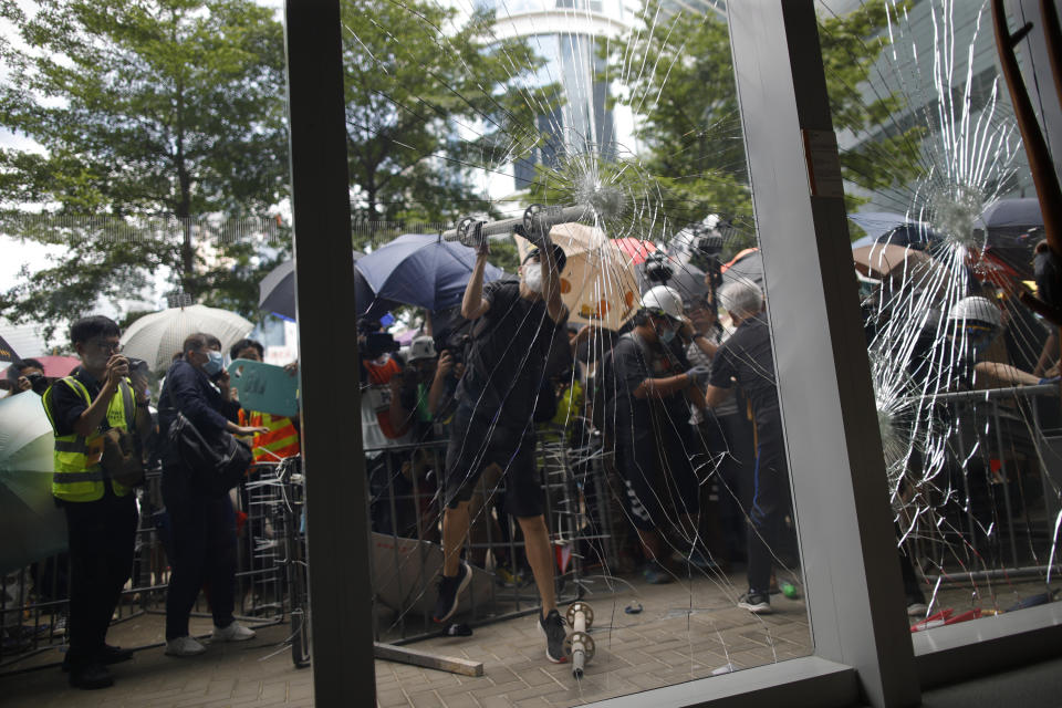 A protester tries to break the glass to get into the Legislative Council in Hong Kong Monday, July 1, 2019. Combative protesters are staging a protest outside the Hong Kong legislature as a crowd of thousands prepares to start a march in that direction. (Jeff Cheng/HK01 via AP)