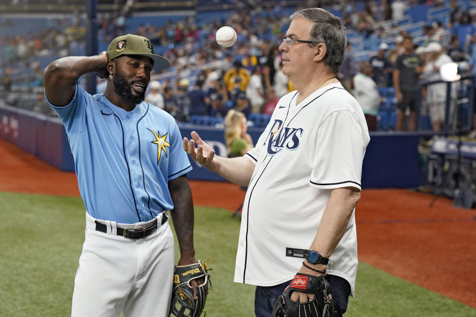 Marcelo Ebrard, right, Mexico's Secretary of Foreign Affairs, flips a ball as he talks to Tampa Bay Rays' Randy Arozarena before a baseball game between the Rays and the Milwaukee Brewers Sunday, May 21, 2023, in St. Petersburg, Fla. (AP Photo/Chris O'Meara)