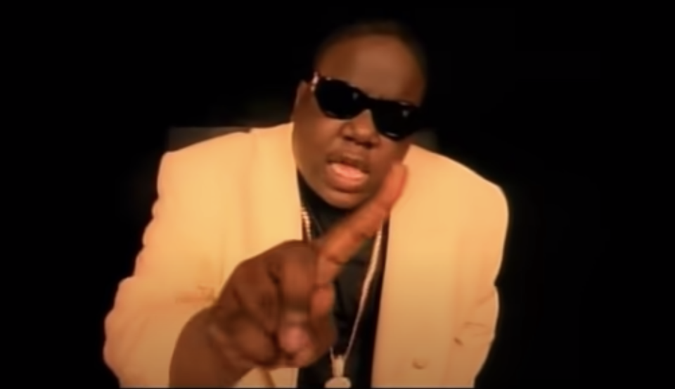 Biggie in a white suit and rapping in a video