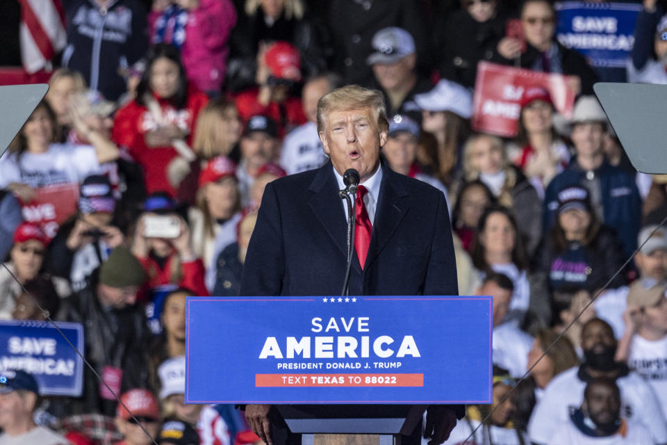 Former President Donald Trump speaks at a rally at a podium with a microphone and sign that reads: Save America