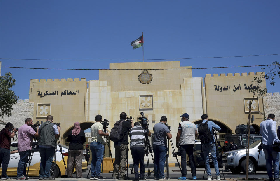 Reporters stand outside the state security court where the trial of Bassem Awadallah, a former royal adviser, and Sharif Hassan bin Zaid, a distant cousin of the king, is taking place, in Amman, Jordan, Monday, June. 21, 2021. Awadallah, who has Jordanian, U.S. and Saudi citizenship, and bin Zaid, pleaded not guilty Monday to sedition and incitement charges, a defense lawyer said. The defendants are accused of conspiring with a senior royal — Prince Hamzah, a half-brother of the king — to foment unrest against the monarch while soliciting foreign help. (AP Photo/Raad Adayleh)