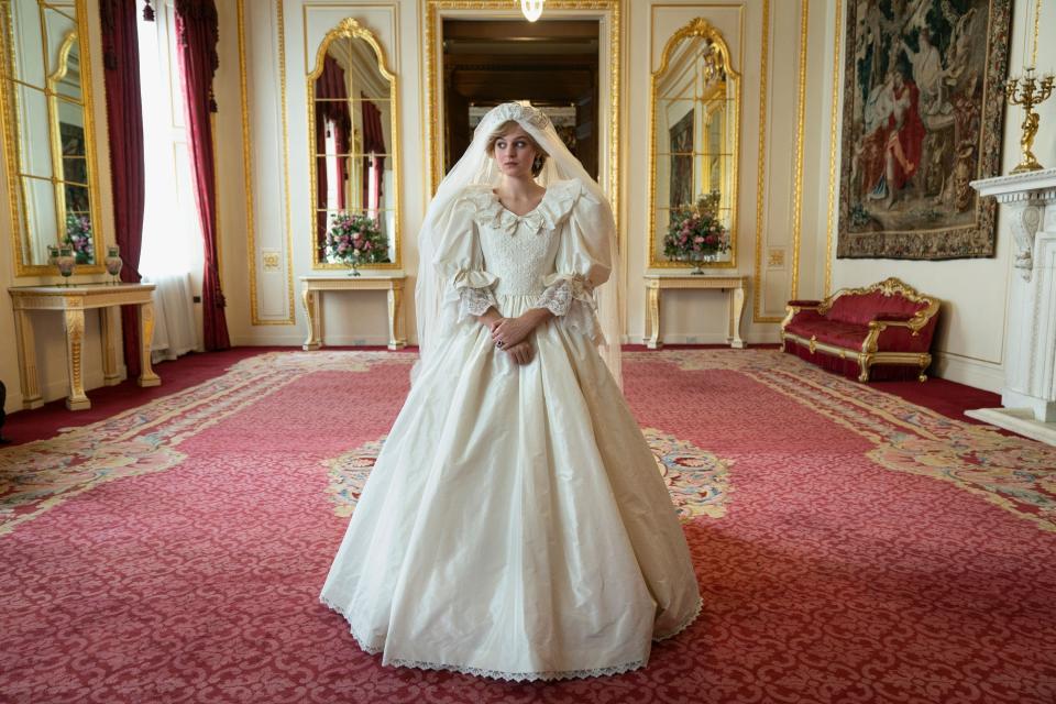 Emma Corrin standing in a very similar gown