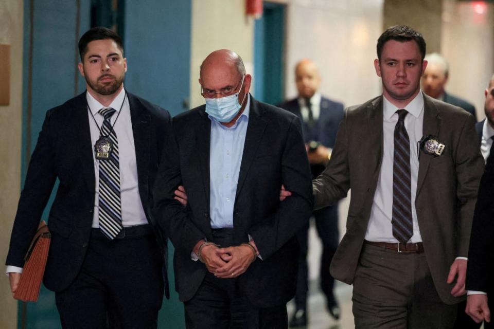 Two men escort a handcuffed Allen Weisselberg out of court.