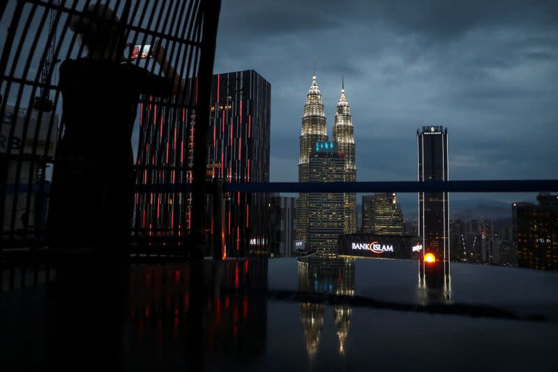 A tourist takes a picture of the city skyline at a bar in Kuala Lumpur