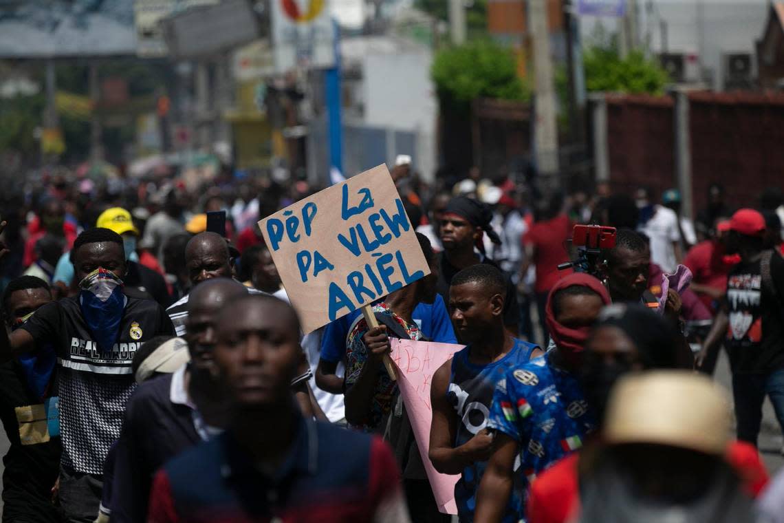 A man carries a sign with a message that reads in Creole;  