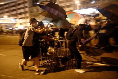 Anti-extradition demonstrators run to barricade the road against the police, after a march to call for democratic reforms in Hong Kong