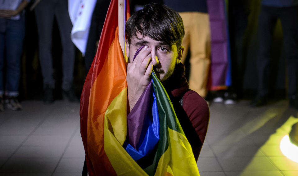 A man sits draped in a rainbow flag in a nightclub in Bucharest, Romania, Sunday, Oct. 7, 2018, after hearing of the partial voter turnout. Polls have closed in Romania after two days of voting on a constitutional amendment that would make it harder to legalize same-sex marriage. But the weekend referendum to redefine marriage failed to attract large numbers of voters and risk being voided. (AP Photo/Andreea Alexandru)