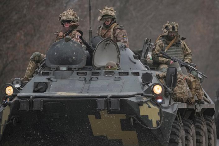 Ukrainian servicemen sit atop armored personnel carriers driving on a road in the Donetsk region, eastern Ukraine, Thursday, Feb. 24, 2022. Russian President Vladimir Putin on Thursday announced a military operation in Ukraine and warned other countries that any attempt to interfere with the Russian action would lead to &quot;consequences you have never seen.&quot;