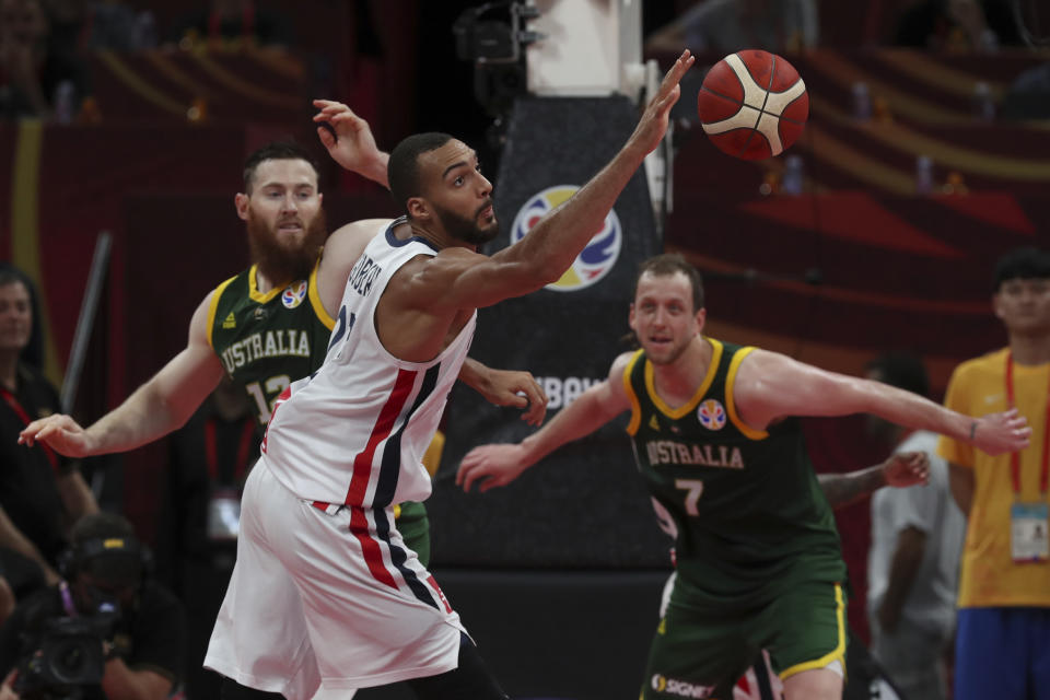 Rudy Gobert of France reaches for the ball over Aron Baynes, left, and Joe Ingles, right, of Australia during their third placing match for the FIBA Basketball World Cup at the Cadillac Arena in Beijing, Sunday, Sept. 15, 2019. (AP Photo/Ng Han Guan)
