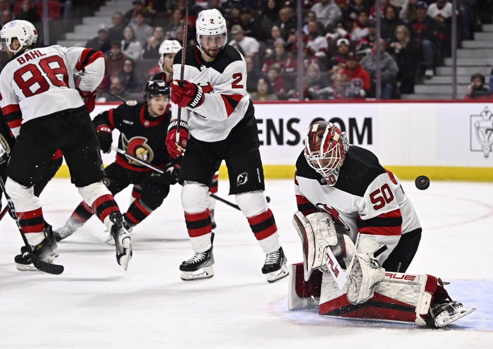 The puck gets past New Jersey Devils goaltender Nico Daws (50) during the second period of an NHL hockey game against the Ottawa Senators, Friday, Dec. 29, 2023 in Ottawa, Ontario. (Justin Tang/The Canadian Press via AP)