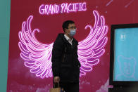 A man wearing a mask to protect from the coronavirus passes by neon lights along a retail street in Beijing Tuesday, March 2, 2021. The state of the world's second largest economy takes precedence among the myriad issues presented by Premier Li Keqiang in his address at the National People's Congress opening session to take place on Friday, March 5. 2021. (AP Photo/Ng Han Guan)