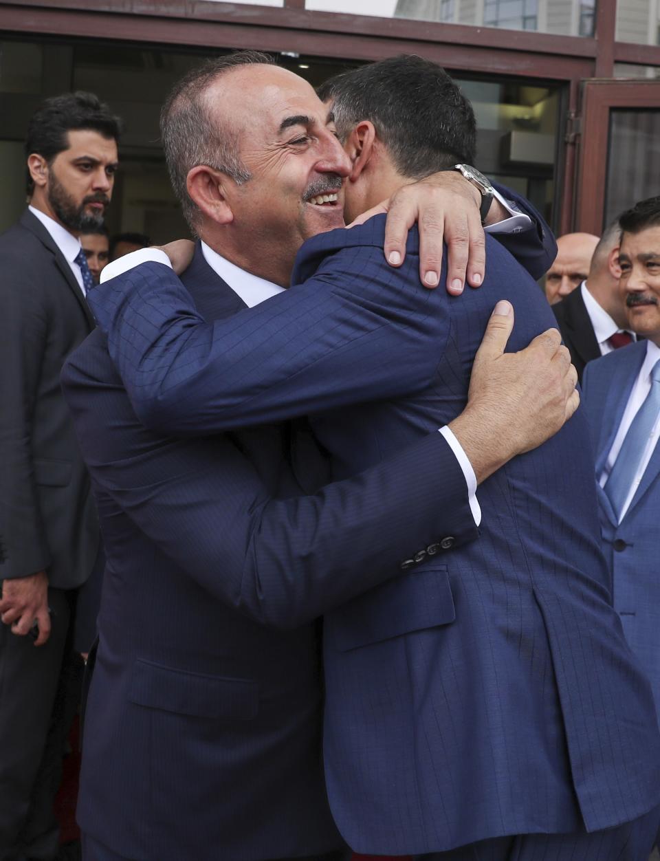 Turkey's Foreign Minister Mevlut Cavusoglu, left, embraces North Macedonia's Foreign Minister Nikola Dimitrov, right, prior to their meeting, in Skopje, North Macedonia, Tuesday, July 16, 2019. Cavusoglu on Tuesday downplayed as "worthless" an initial set of sanctions approved by the European Union against Ankara and vowed to send a new vessel to the eastern Mediterranean to reinforce its efforts to drill for hydrocarbons off the island of Cyprus. EU foreign ministers on Monday approved sanctions against Turkey over its drilling for gas in waters where EU member Cyprus has exclusive economic rights. (Cem Ozdel/Turkish Foreign Ministry via AP, Pool)