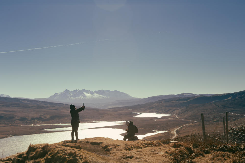 Young couple watching the scenic view - Raasay island and the mainland of Scotland from the Storr Trail, Isle of Skye