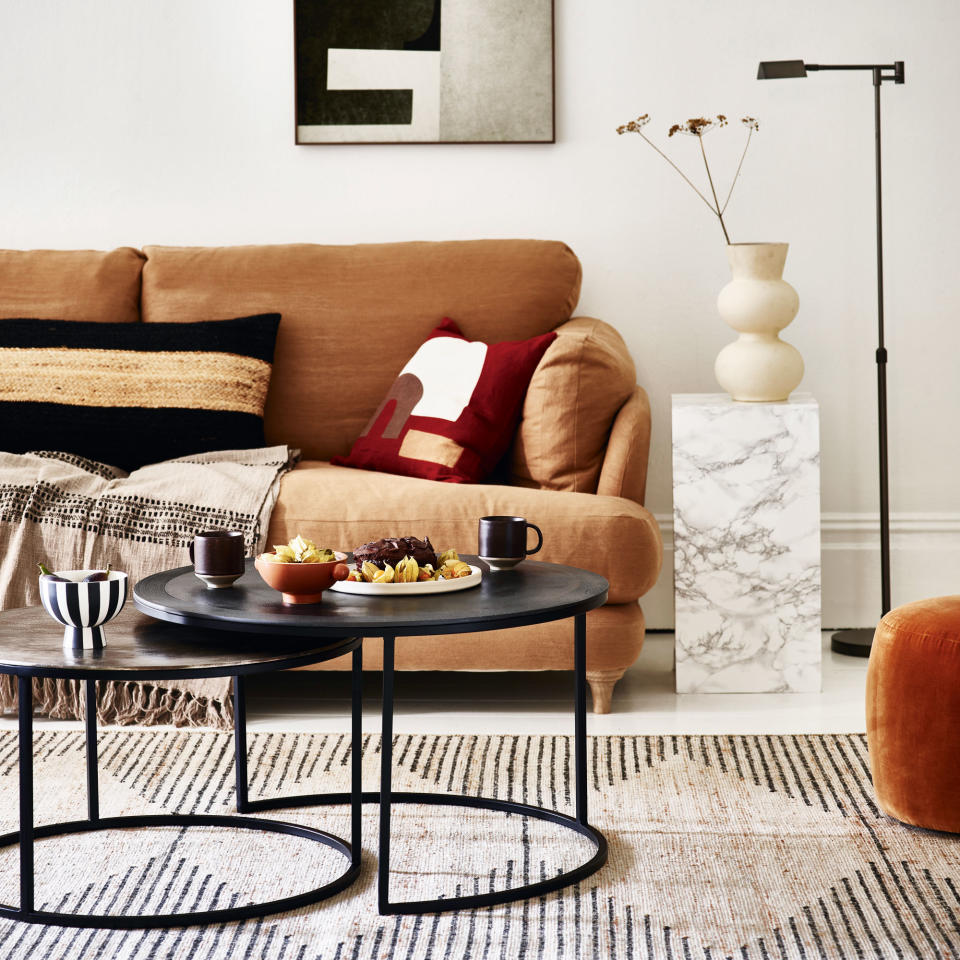 living room with brown sofa, rug and black nested tables