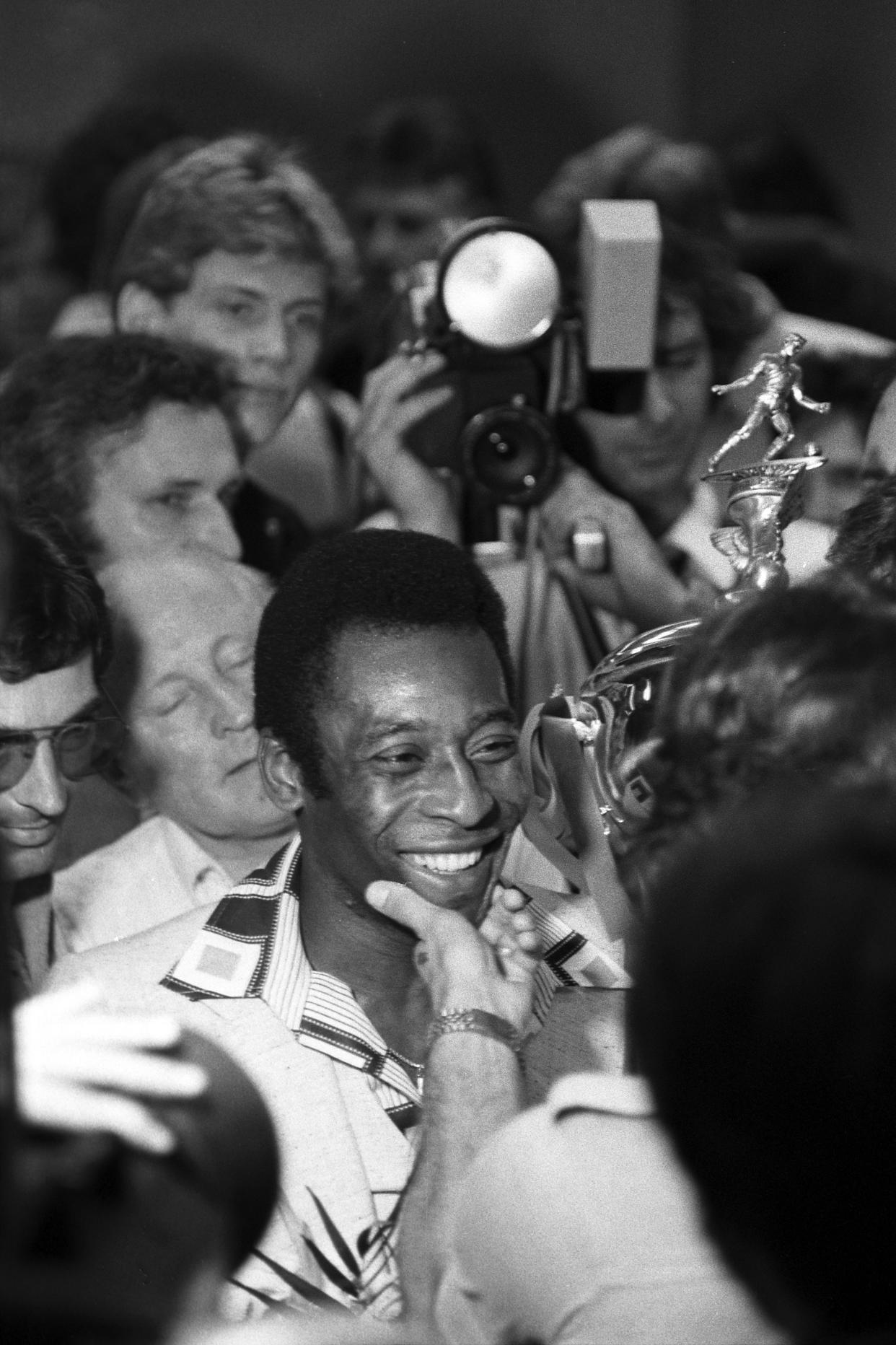 Periodistas y simpatizantes rodean a Pelé, quien lleva el trofeo de campeón de la North American Soccer League de 1977, en el aeropuerto John F. Kennedy de Nueva York, el 29 de agosto de 1977. (Chester Higgins Jr./The New York Times)