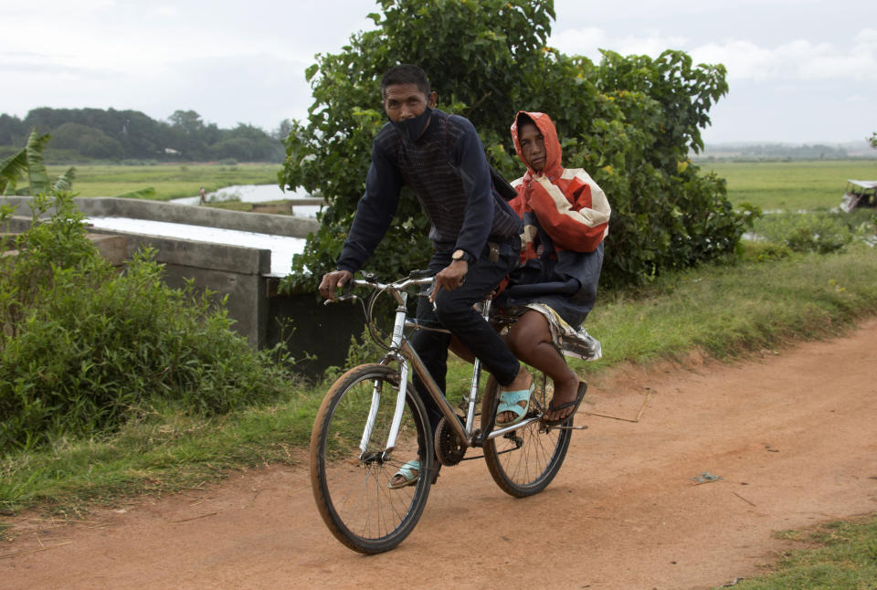 A man and his wife make their way home during adverse weather in Antananarivo, Madagascar, Saturday, Feb. 5, 2022. Weather officials forecast that the full force of Cyclone Batsirai is to hit Madagascar Saturday evening. Madagascar's meteorology department said the cyclone is gaining strength as it blows across the Indian Ocean, with gale-force winds reaching peaks of 235 kilometers (145 miles) per hour. (AP Photo/Alexander Joe)