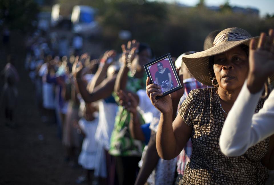 In this Feb. 8, 2014 photo, a Christian pilgrim holds a picture of her daughter during a procession in the village of Bois-Neuf, Haiti. Some brought their passports in hopes that their prayers may help them secure a visa to leave impoverished Haiti. Others held aloft photos of sick family members in hopes that their prayers will rid them of illness. (AP Photo/Dieu Nalio Chery)