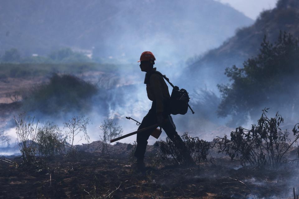 A US Forest Service firefighter sets a controlled burn as the Post Fire burns through Castaic, California, June 16, 2024. The fire has grown to 12,265 acres, and continues to move southeast of Pyramid Lake, according to the US Department of Agriculture Forest Service at Angeles National Forest.