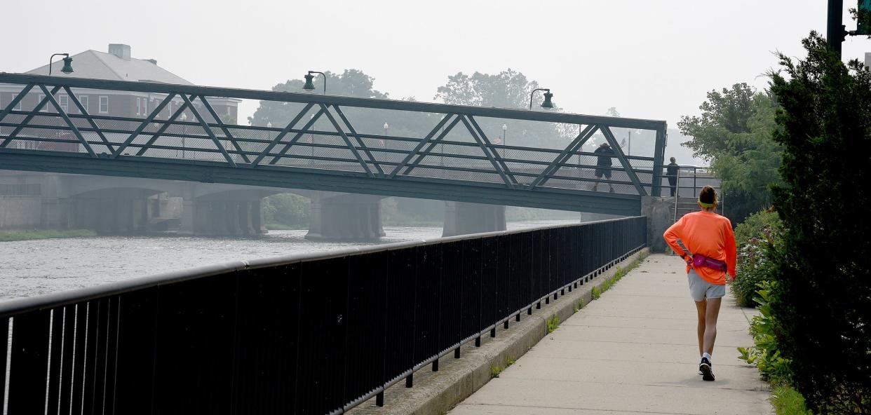 Walkers are pictured Thursday at the Martin Luther King Jr. Bridge in Monroe in what looks like fog but is actually smoke from Canadian wildfires that has led to air quality alerts this week in Michigan, including Monroe County.